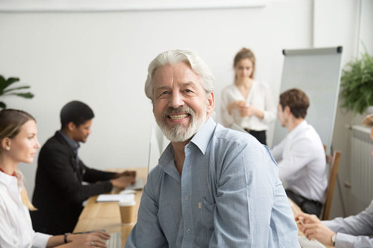 Un chef d’équipe âgé sourit dans une salle de réunion.