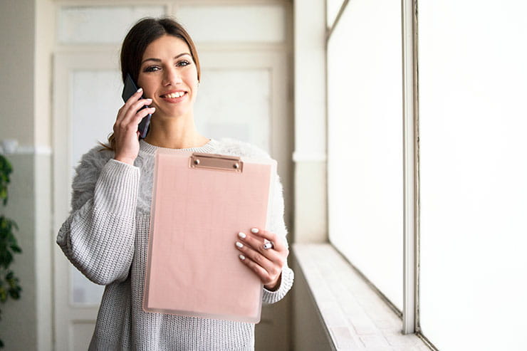 Exemples de questions et réponses : Jeune femme au téléphone tenant une planchette à pince au travail