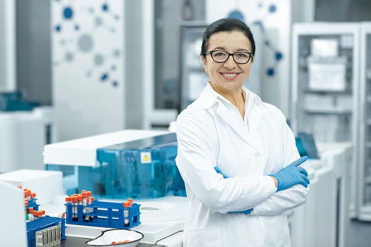 Middle-aged female life science researcher smiles in her laboratory