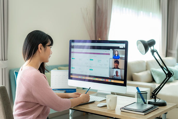An employee collaborating with her colleagues virtually on her desktop. 