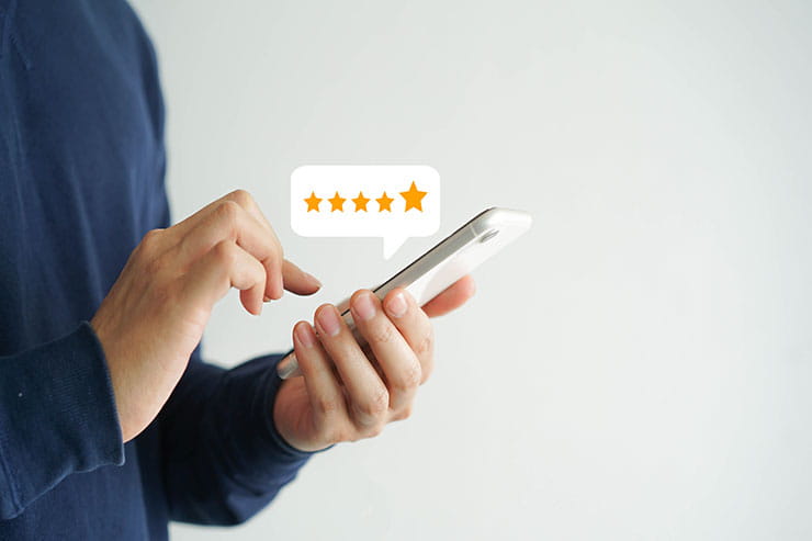 Close-up of a person using their smartphone to leave an online review.