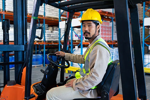 Asian forklift driver at a warehouse.